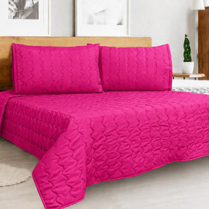 Cover acolchado Arlin color fucsia de microfibra con diseño punzonado y fundas de almohada a juego sobre cama